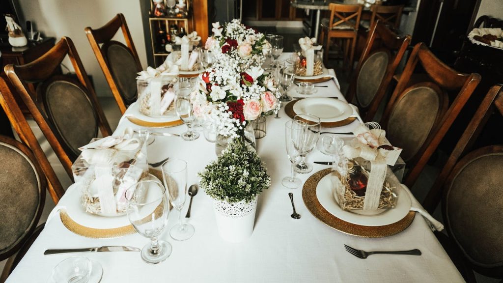 A beautifully arranged dining table with floral centerpieces and wrapped gift boxes, ready for a special event.